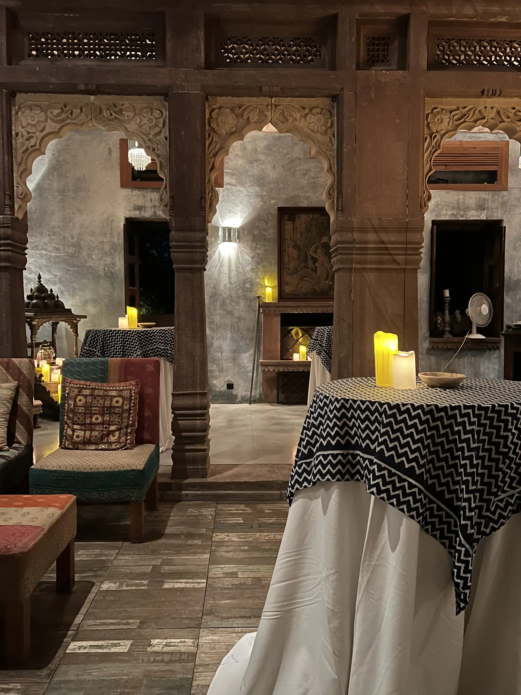The candlelit sandstone arcade at night, carved arches and block-print tables set for dinner